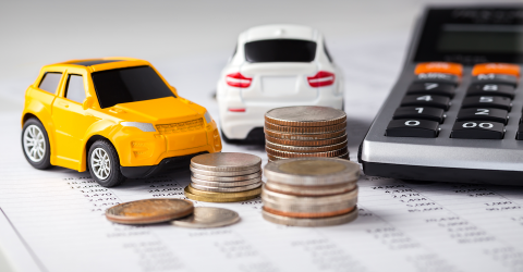 En gele en witte kleine speelgoedauto op een papier met een stapel munten en een rekenmachine